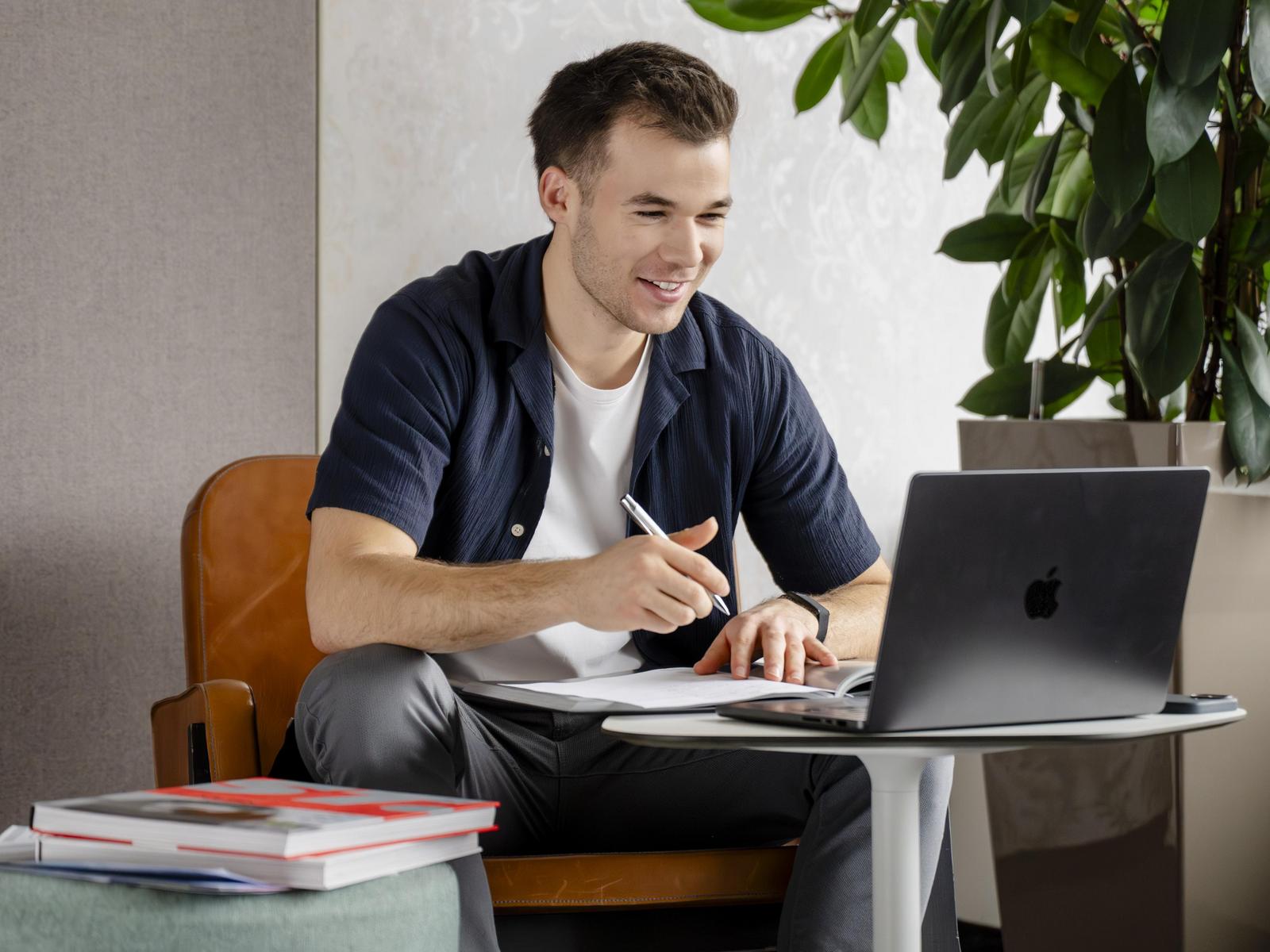 Mitarbeiter lernt, arbeitet am Notebook und lernt aus Büchern.