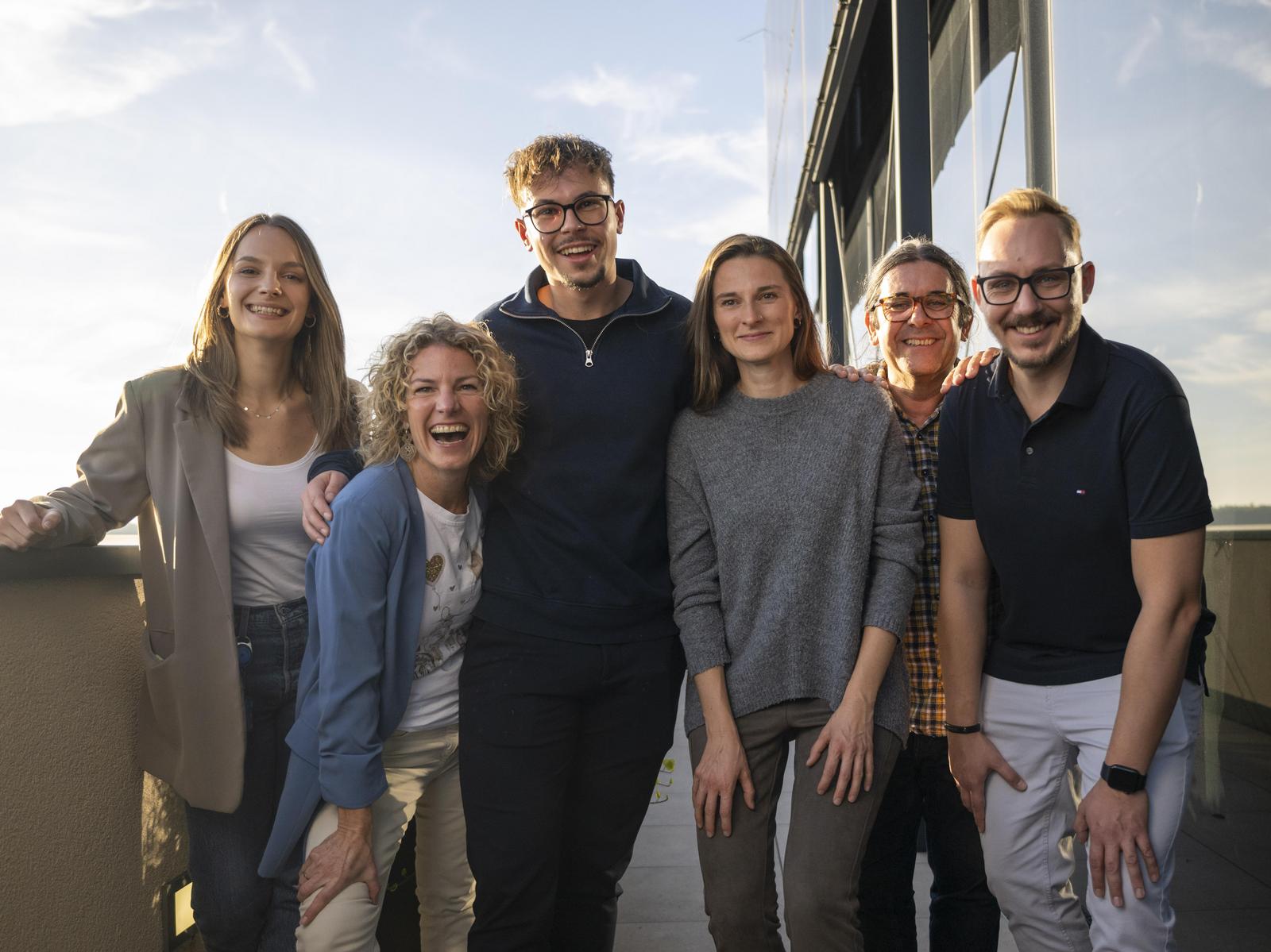 Mehrere Mitarbeitende stehen gemeinsam auf der Terrasse und arbeiten gemeinsam.