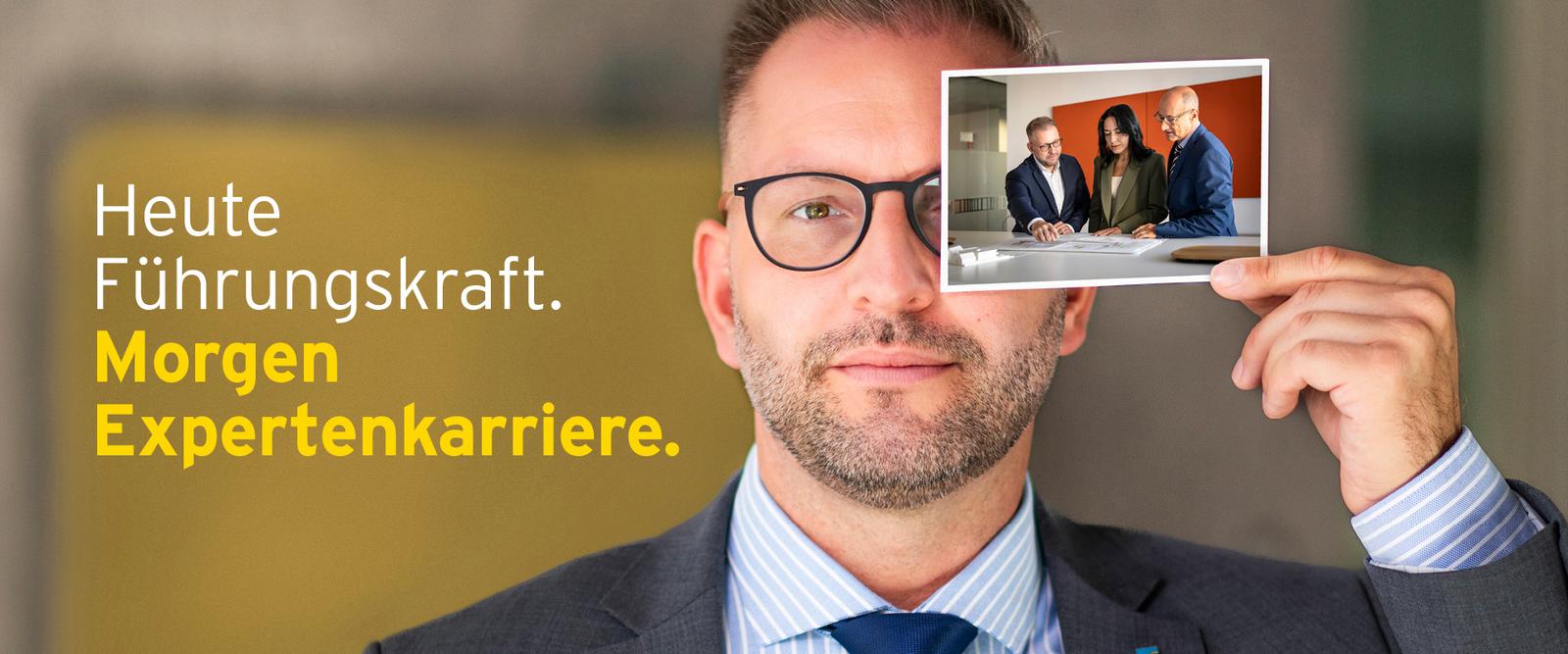 Mitarbeiter hält Foto, welches zeigt, wie er als Experte arbeitet. Heute Führungskraft. Morgen Expertenkarriere.